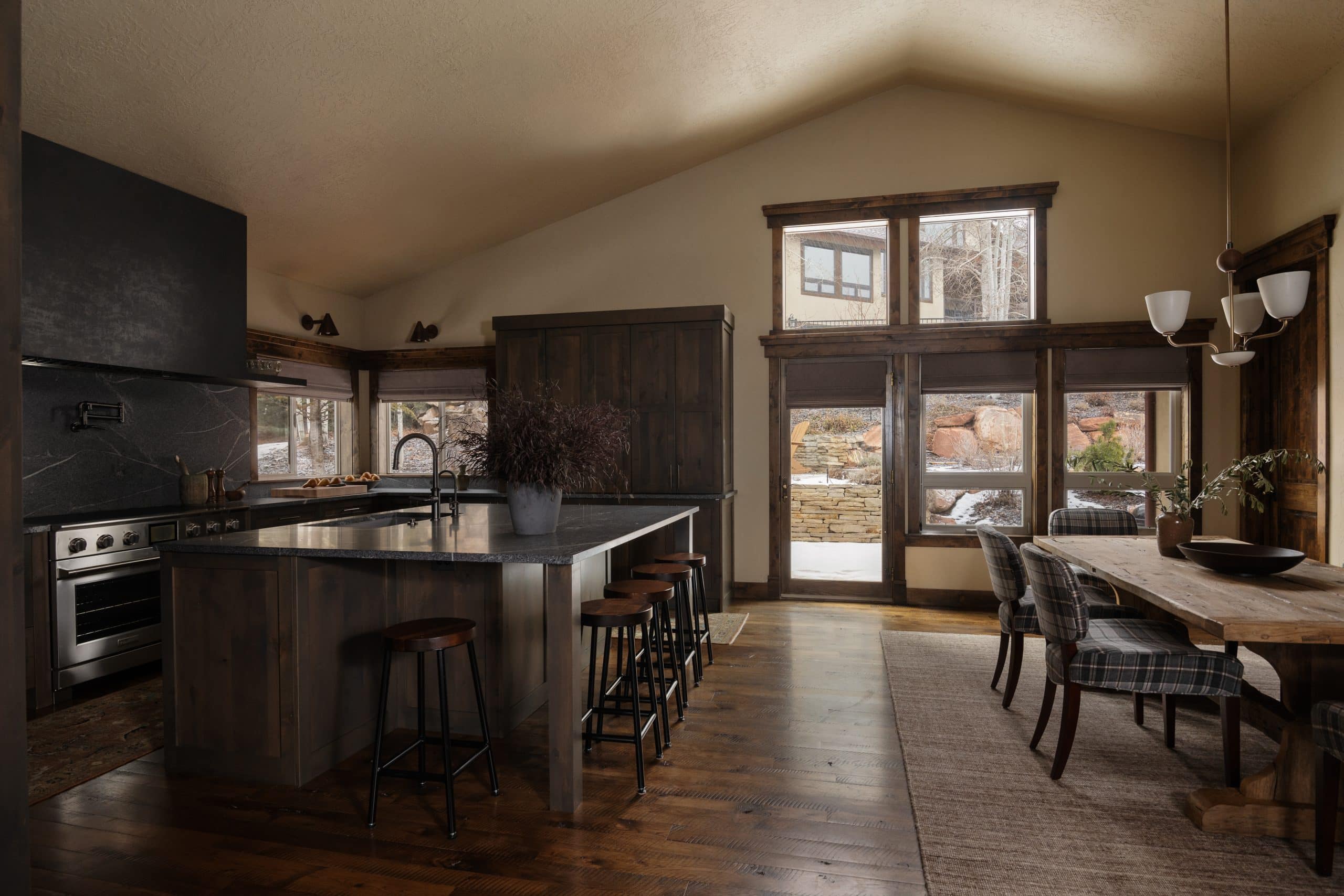 Open kitchen and dining space with a stone-topped island and windows overlooking the terrace