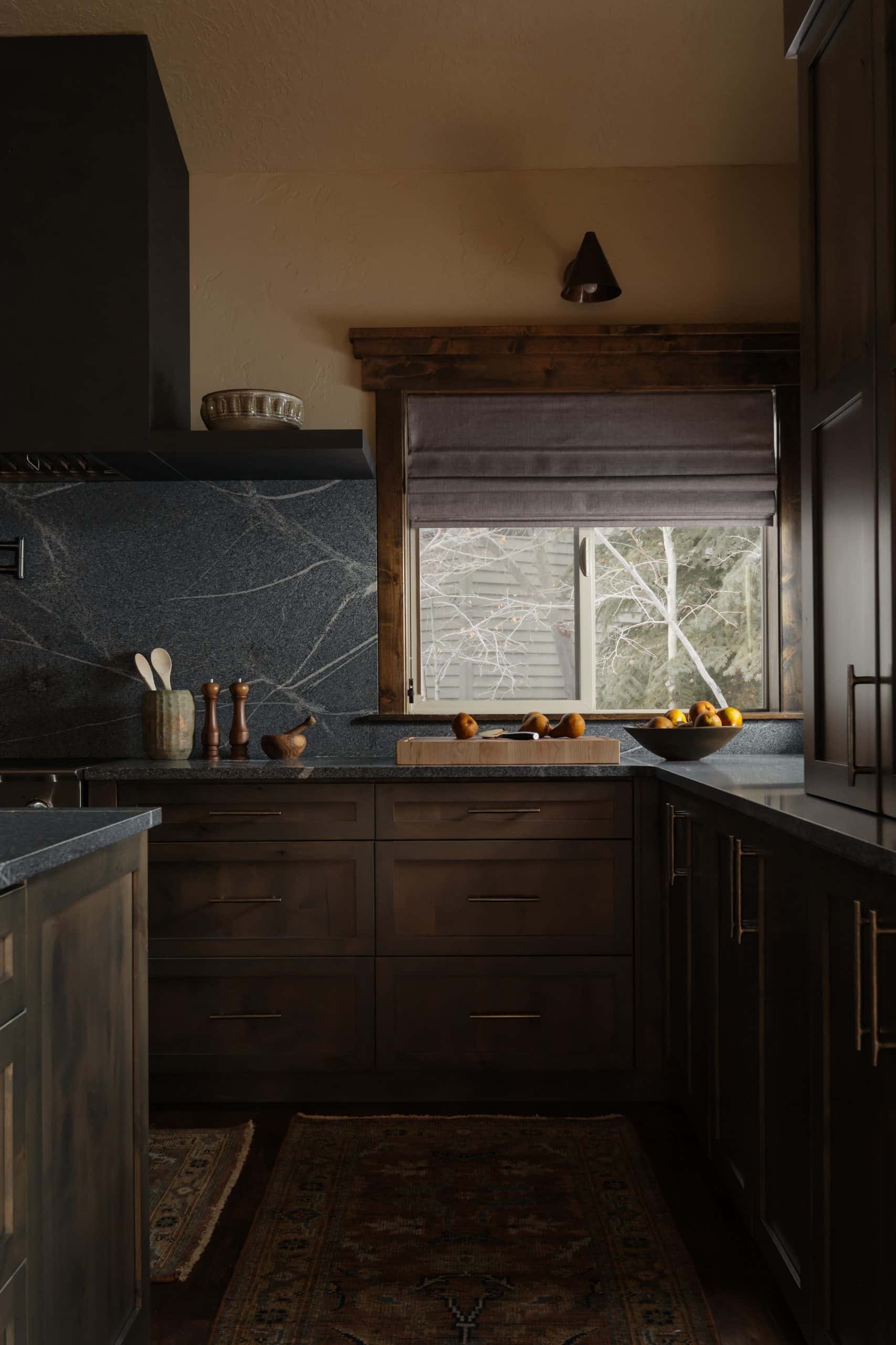 Kitchen corner with veined stone backsplash, roman shade, and a runner rug along wood floors