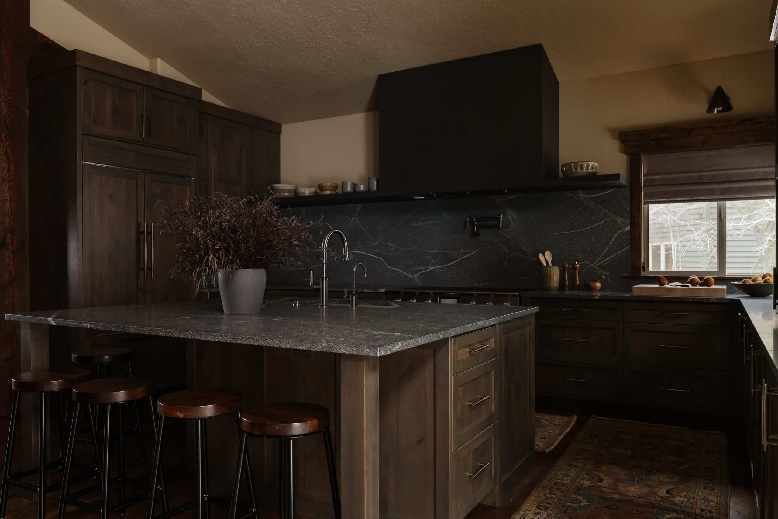 Kitchen with dark stone island and backsplash, wood cabinetry, and a window over the sink