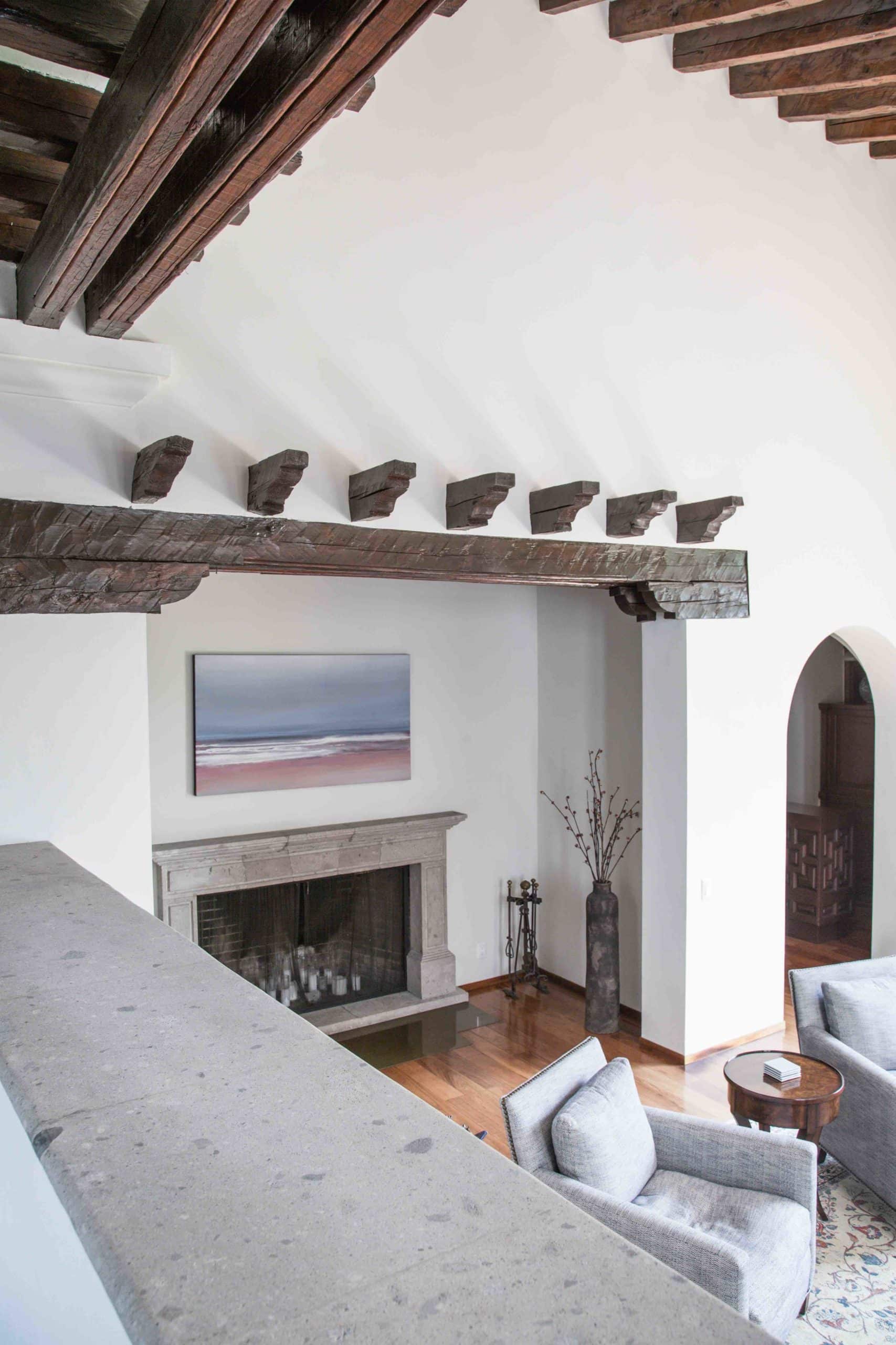 Wood beam ceiling with hand-cut corbels above a stone fireplace