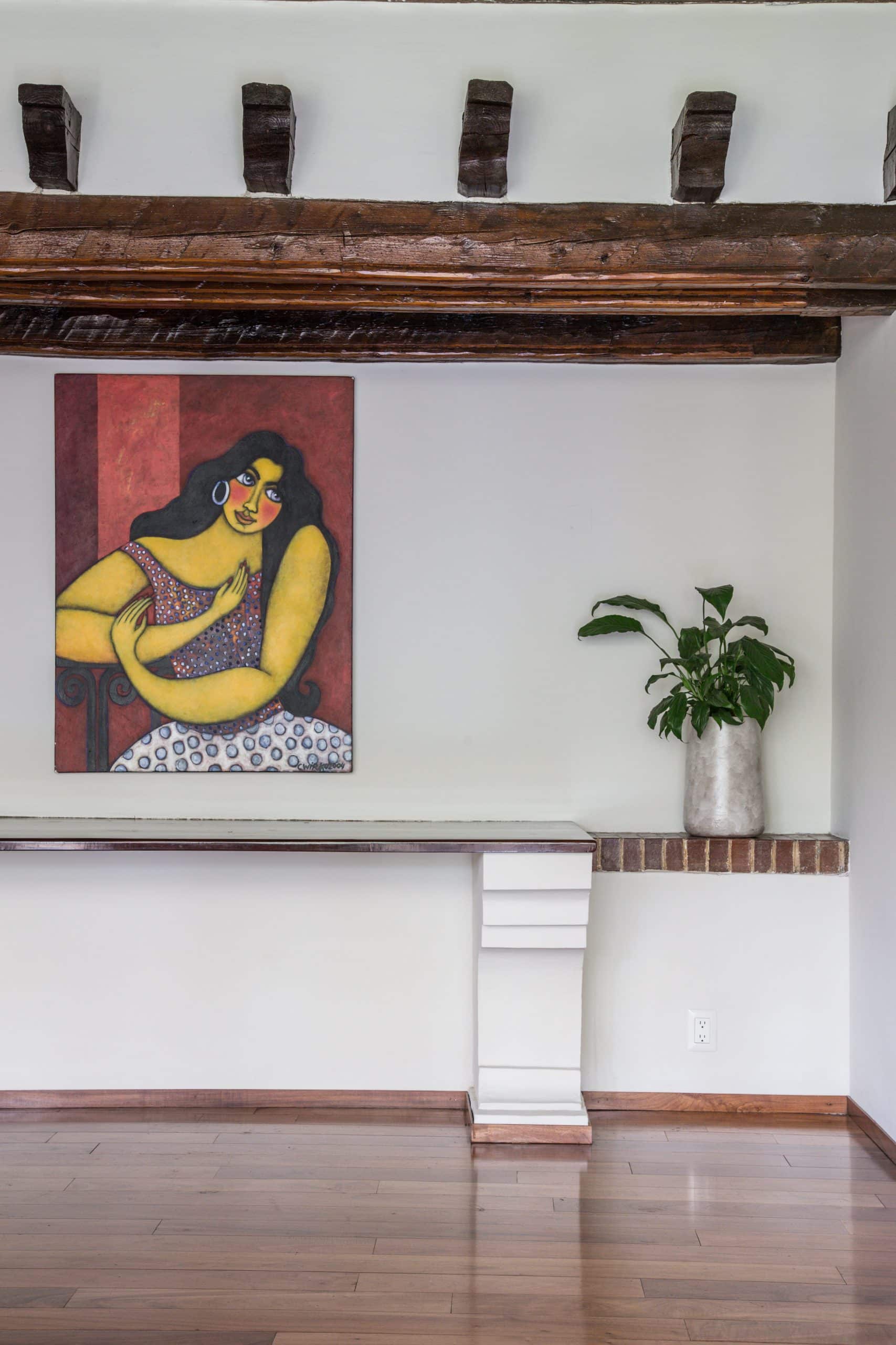 Mexican artwork beneath exposed wood beams with hand-cut corbels