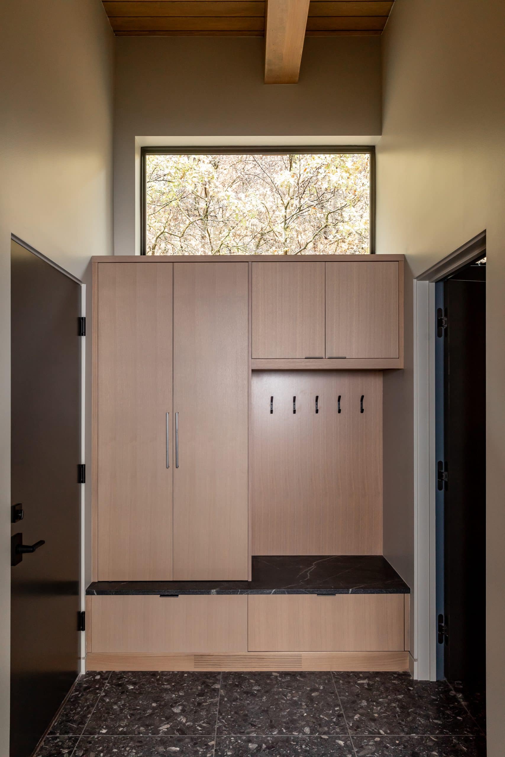 Mudroom with light oak built-in cabinetry, coat hooks, a stone bench seat, and terrazzo floor