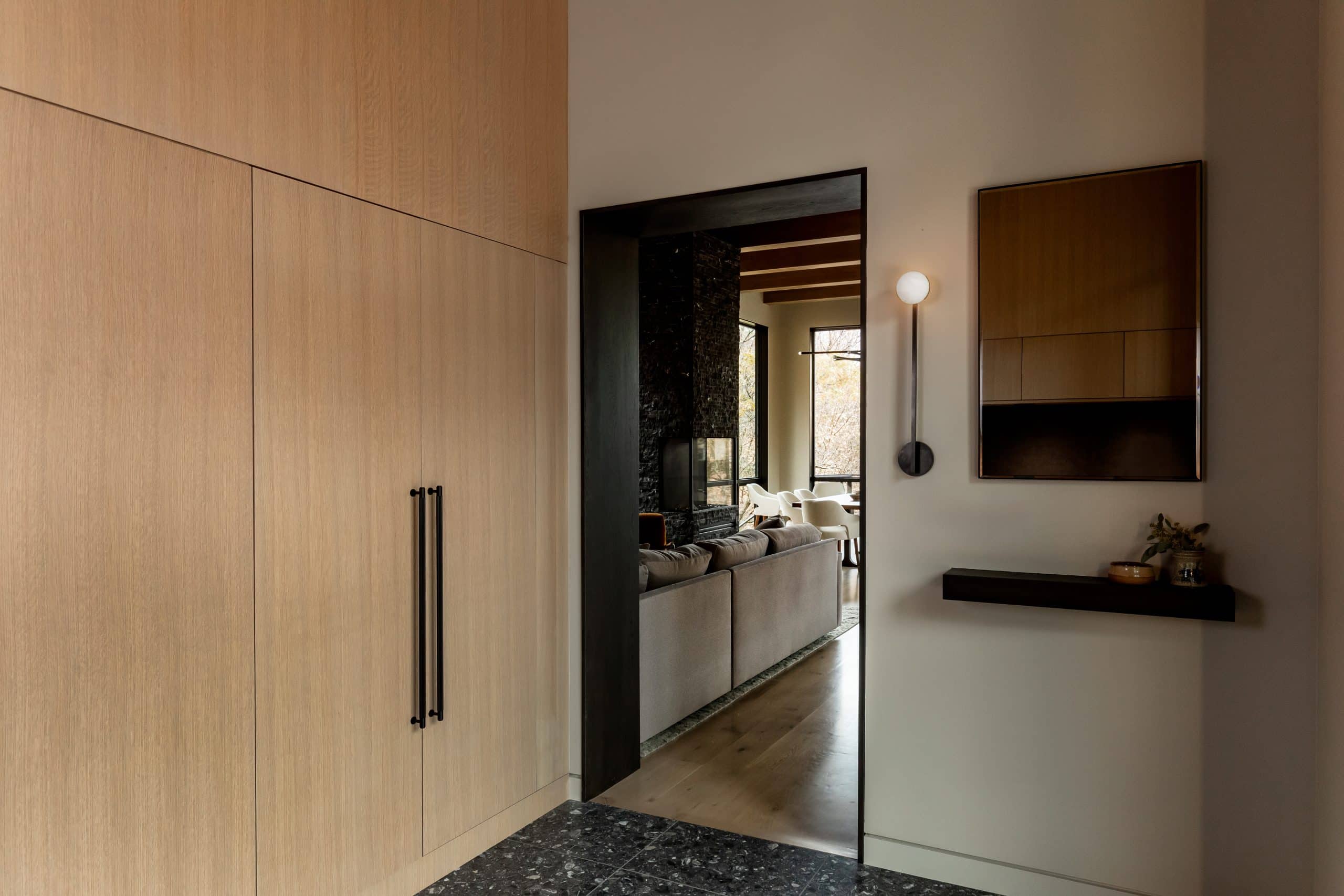 Entry vestibule with floor-to-ceiling oak cabinetry opening onto the living room beyond