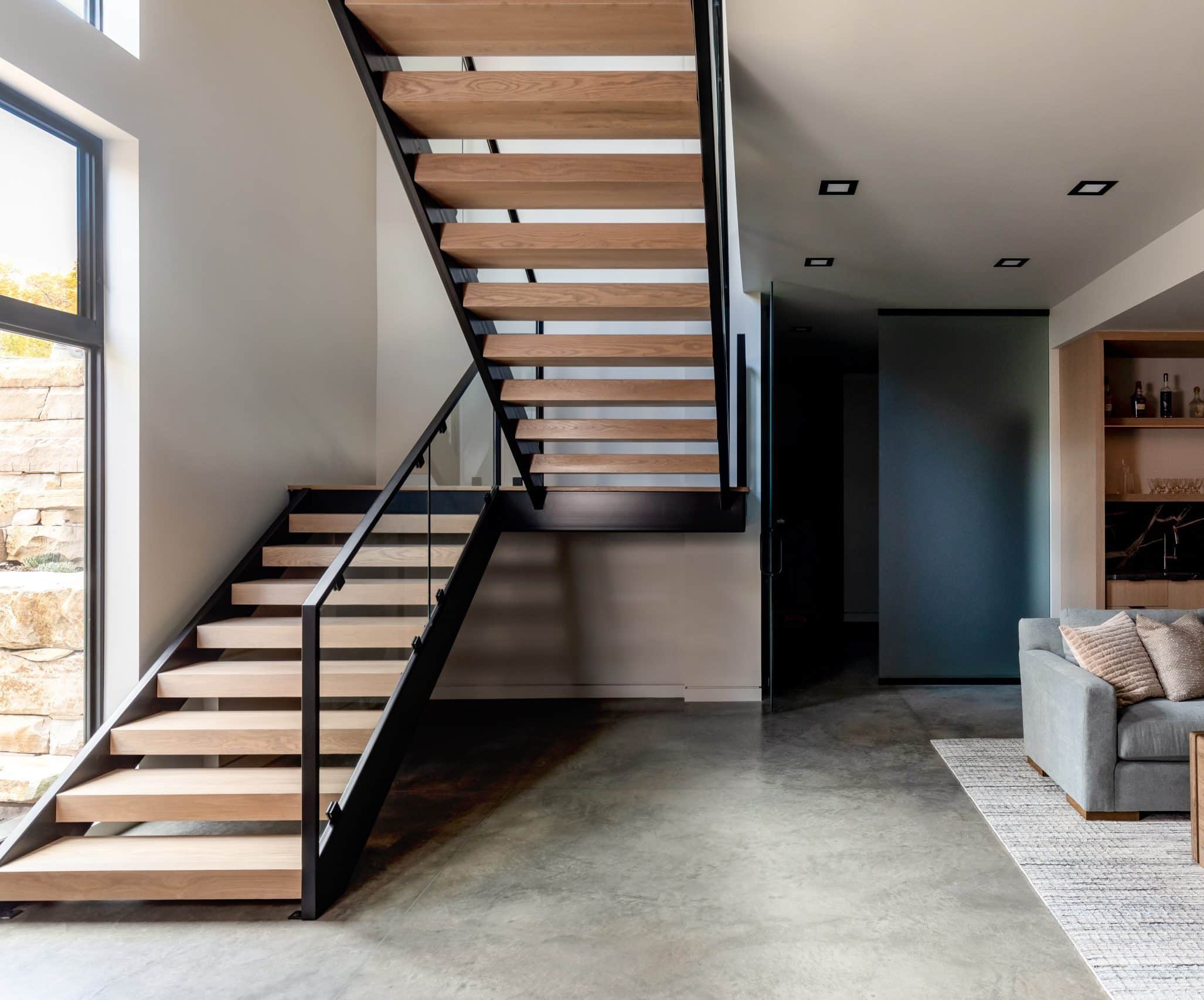 The finished great room with a floating oak-and-steel staircase over a polished concrete floor