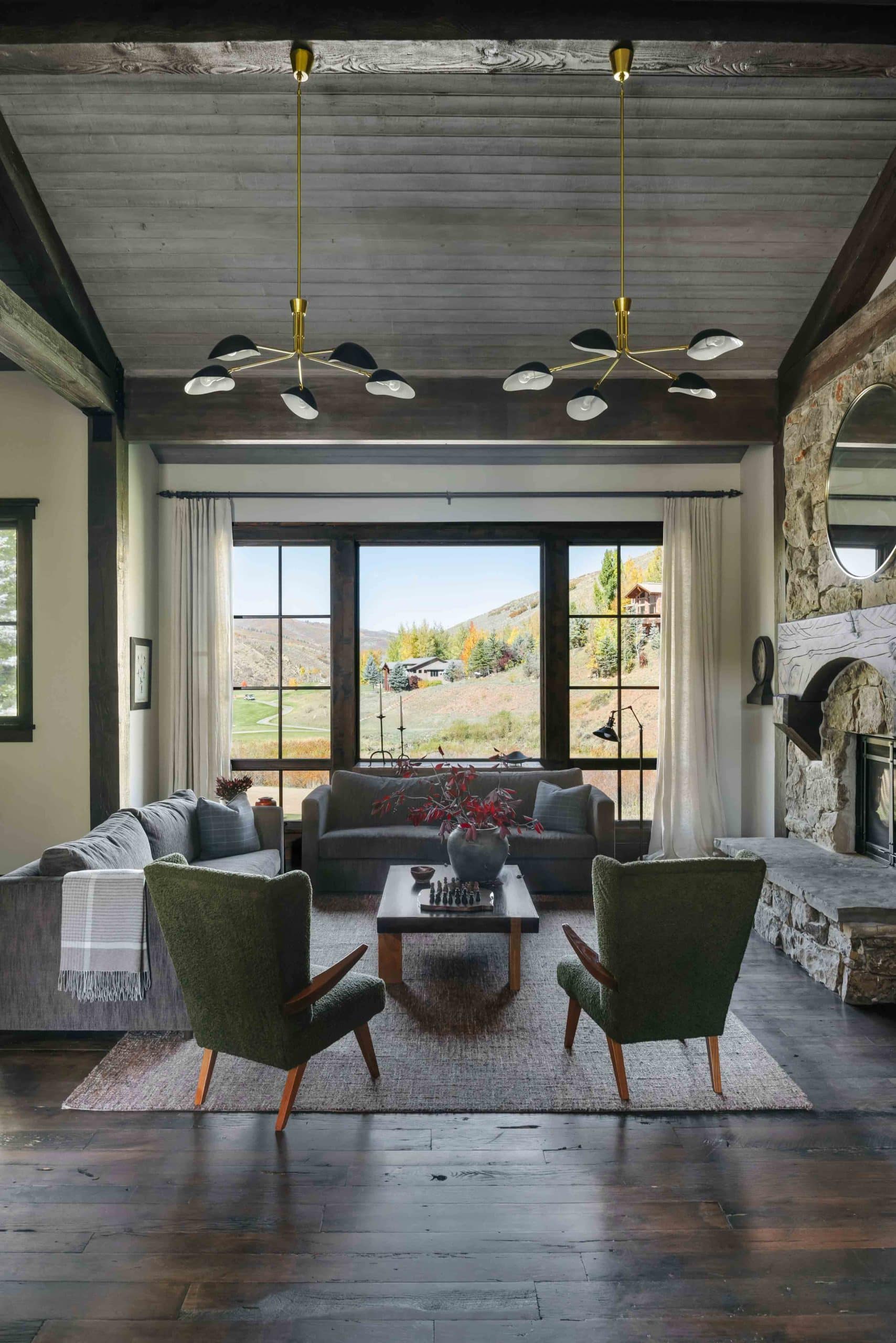 Living room with a stone fireplace, wood-beamed ceiling, and layered neutral seating